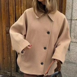 Détail d'une veste en laine camel oversize avec boutons noirs et manches larges évasées