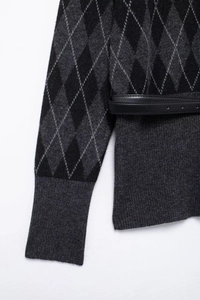 Detail of argyle knit sweater with ribbed cuffs and a black leather waist belt