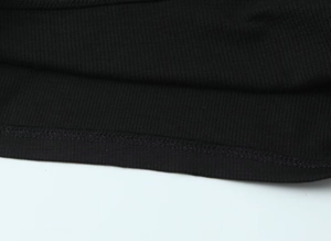 Detailed macro view of the ribbed knit fabric texture and smooth stitched edge on a black tee