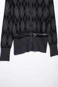 Detail view of knitted cardigan with argyle pattern and black thin belt with silver buckle