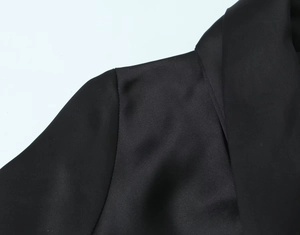 Detailaufnahme eines schwarzen Satinblazers mit Fokus auf Schulternaht und Kragenlinie