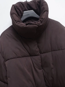 Detail of dark brown quilted puffer jacket featuring high stand collar and thermal texture