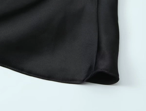 Detailaufnahme der schwarzen Satinstoffstruktur mit Seidenglanz und feinen Nähten am Kleid