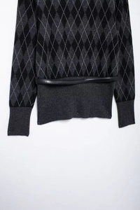 Detail of grey and black argyle knit cardigan with black leather belt and ribbed cuffs