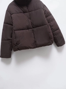 Detail of deep brown quilted jacket featuring stand collar and warm puffer insulation