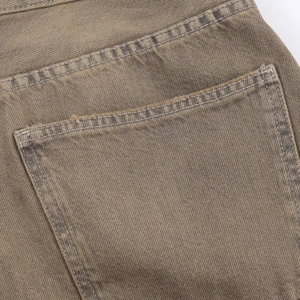 Detail shot of vintage brown denim back pocket with double stitching and distressed edges