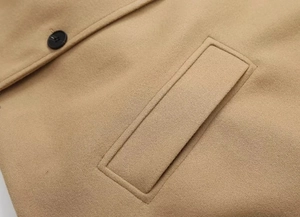 Gros plan de la veste en laine camel montrant la poche à rabat et le tissu premium