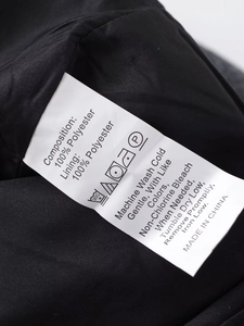 Détail de l'étiquette de lavage indiquant 100% polyester sur la veste noire