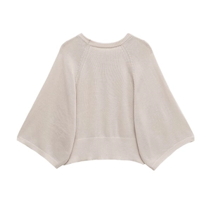 Close-up of cream knit sweater showing fine ribbed neckline and wide raglan sleeves