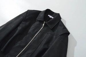 Detail of black faux leather bomber jacket showing lapel, silver zipper and collar label