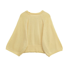 Detailed view of pale yellow knit sweater featuring ribbed cuffs and soft texture
