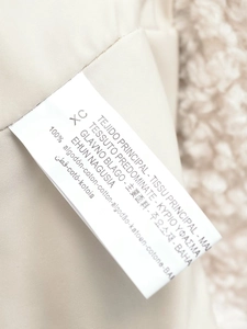 Détail de l'étiquette d'entretien montrant la taille XC et la composition 100% coton du tissu