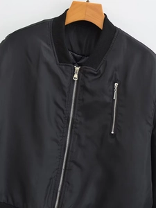 Detail view of a black bomber jacket featuring a ribbed collar and silver metal zippers