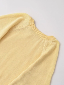 Close-up of crew neckline and ribbed shoulder detail on light yellow knit sweater