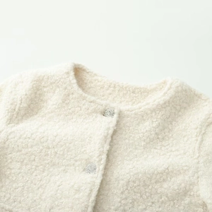 Détail d'une veste en bouclée avec col rond et boutons décoratifs argentés élégants