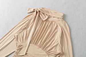 Detail view of beige ribbed knit top with neck bow and elegant shirred texture