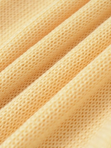Detailed macro shot of light yellow knit fabric showing soft texture and mesh weave pattern