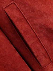 Dettaglio macro della texture in finta pelle scamosciata rossa e cuciture rifinite