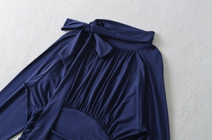 Detail of navy blue blouse showing bow-tie collar and intricate pleated texture