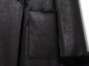 Detailed macro view of black faux fur trim and polished leather texture on a long winter coat