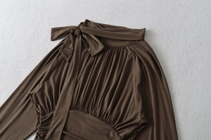 Detailed view of coffee brown long sleeve shirt with elegant bow tie and pleated fabric