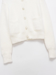 Close-up of white plush knit cardigan featuring decorative silver buttons and front pockets