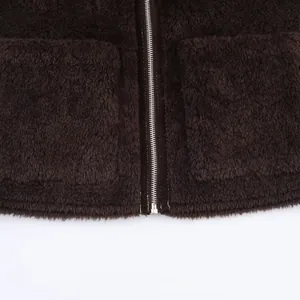 Dettaglio dell'orlo della giacca in pile marrone con zip in metallo e ampie tasche applicate