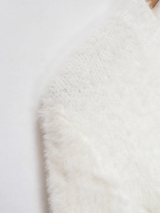Close-up of white plush knit cardigan showing soft faux fur texture and sewing detail