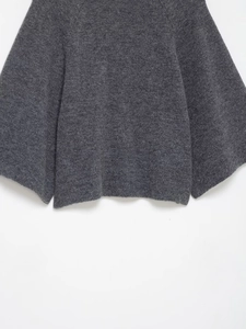 Close-up of thick dark grey knit fabric texture on wide sleeves and hem of sweater