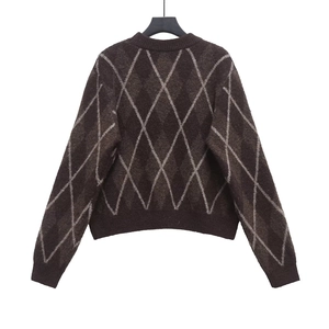Detail of dark brown knit sweater with grey argyle pattern and ribbed cuffs and collar