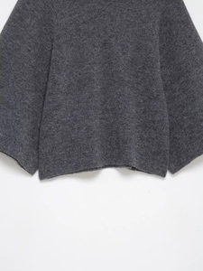 Detail of dark grey knit sweater showing thick wool texture and ribbed hem craftsmanship