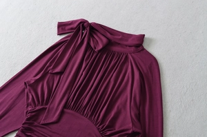 Detail of elegant bow neckline and pleated texture on deep purple long-sleeve blouse