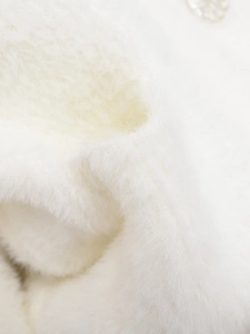 Close-up of white plush faux fur fabric with soft texture and metallic button detail