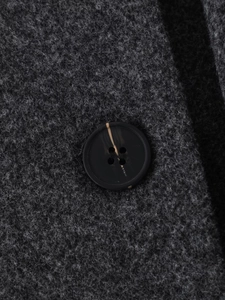 Detail of dark gray wool coat showing a marble pattern button and premium fabric texture