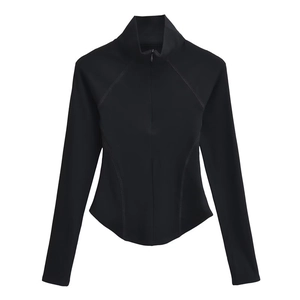 Détail d'un haut de yoga noir ajusté avec col montant zippé et ourlet courbé élégant