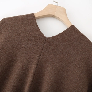 Detail showing the thick brown knit texture and V-neckline of a long winter cardigan