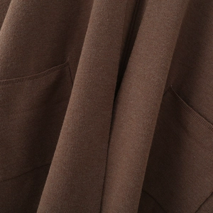 Close-up of dark brown knit texture and flat stitching detail on the long pocket cardigan