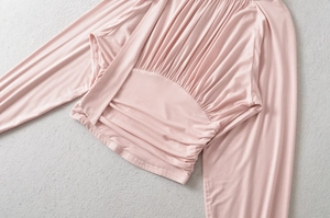 Detailed flat lay of pink long-sleeve shirt featuring elegant ruching and cinched waist