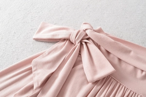 Detail of the soft pink long sleeve top showing the bow tie knot and pleated texture