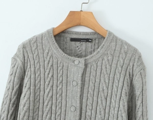 Detail of grey cable-knit cardigan showing round neckline and buttoned front