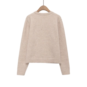 Close-up of oatmeal knit sweater showing ribbed crew neck and soft fabric texture
