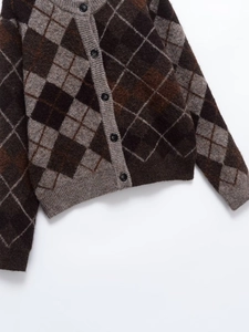 Detail of diamond pattern knit cardigan with black buttons and V-neckline texture