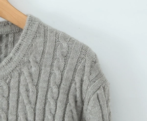 Detailed close-up of gray cable-knit texture and soft fabric of the knitwear top