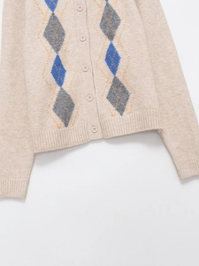 Detail of argyle pattern knit cardigan with orange stitching and matte buttons