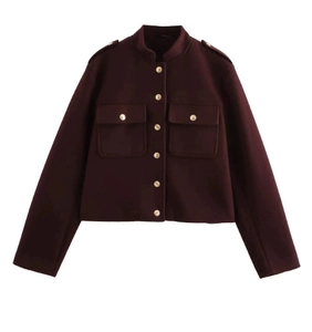 Détail d'une veste courte bordeaux à col montant et boutons métalliques dorés