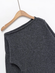 Gros plan sur la texture en maille gris foncé et l'encolure à épaules dénudées du pull