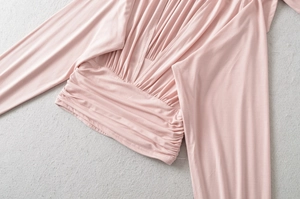 Detailed view of pink long sleeve top with deep V-neck and ruched waist design