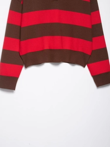 Detailed view of the ribbed hem and cuffs on a striped knit polo sweater in brown and red