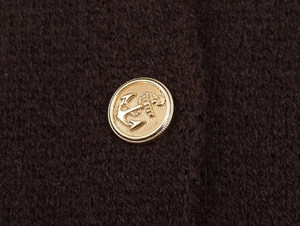 Macro shot of gold anchor-embossed metal button on dark brown chunky knit fabric