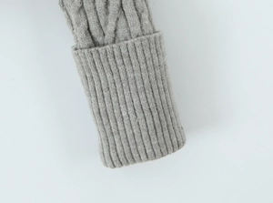 Detailed close-up of thick cable knit texture and ribbed folded cuffs on a grey cardigan